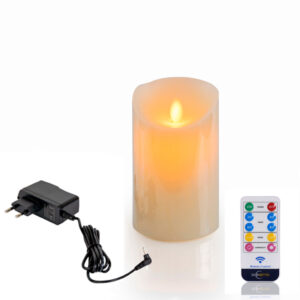 Die wiederaufladbare LED-Wachskerze mit beweglicher Flamme (D 7,5 x 12,5 cm, warmweiß) strahlt realistisch neben einem schwarzen Netzadapter und einer weißen Fernbedienung mit bunten Tasten.