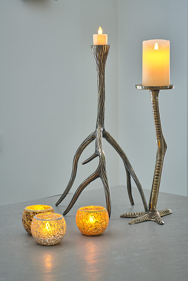 Twee metalen talonvormige kaarsenhouders houden pilaarkaarsen vast, terwijl drie Oplaadbare LED waxinelichtjes met bewegende vlam D 7,5 X 10 CM - warm wit votiefkaarsen gloeien op een grijs oppervlak en een gezellige en uitnodigende sfeer creëren.