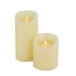 Twee crèmekleurige DORSETTO LED wax kaarsen set 2 maten warm wit oplaadbaar zijn verlicht en staan naast elkaar op een witte achtergrond.