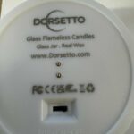 Close-up van de onderkant van een DORSETTO led kaarsen set - oplaadbaar 105 uur, 3D vlam, met afstandsbediening, met de merknaam, productinformatie, certificeringen, website en aan-uitschakelaar.
