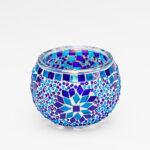 Theelichthouder 9 CM Dorsetto blue is een ronde glazen kandelaar versierd met blauwe, turquoise en paarse mozaïektegeltjes in geometrische patronen op een witte achtergrond.