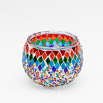 Theelichthouder gekleurde spikkels 9 CM DORSETTO: een ronde glazen kandelaar met kleurrijke ruitvormige mozaïeksteentjes en kleine kraaltjes in rood, groen, blauw, oranje en wit tegen een effen witte achtergrond.