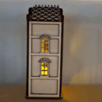 De Waxinelichthouder houten huis DORSETTO, met twee boogramen en een geschulpt dak, werpt een gezellige gele gloed die charme en warmte toevoegt aan elke ruimte wanneer hij tegen een effen muur wordt geplaatst.