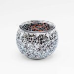 De Theelichthouder zwart 9 CM DORSETTO is een ronde glazen theelichthouder met een mozaïek van kleine, reflecterende zilveren en heldere glazen stukjes, afgebeeld tegen een effen witte achtergrond.