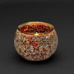 Theelichthouder 9 cm DORSETTO paars is een ronde glazen kandelaar met een levendig paars mozaïekpatroon op een zwarte achtergrond, met reflecterende details voor een opvallende en decoratieve look.