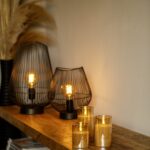 Een houten console tafel met de DORSETTO oplaadbare led kaarsen set (3 stuks, 105 uur brandtijd, met afstandsbediening), moderne draadlampen en droog pampasgras in een zwarte vaas voor langdurige sfeer en gemak.