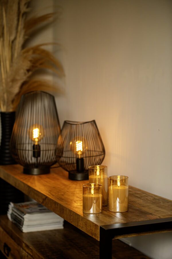 Een houten console tafel met de DORSETTO oplaadbare led kaarsen set (3 stuks, 105 uur brandtijd, met afstandsbediening), moderne draadlampen en droog pampasgras in een zwarte vaas voor langdurige sfeer en gemak.