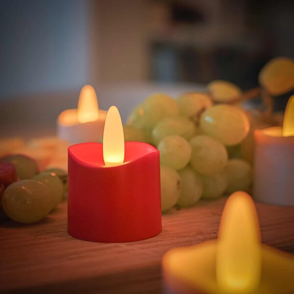 Een close-up van een gloeiend rood LED-kaarsje rood oplaadbaar 175 uur - waterdicht- met Afstandsbediening, afgebeeld naast groene druiven op hout, met andere oplaadbare LED-kaarsjes (12 stuks) en een zacht onscherpe achtergrond.