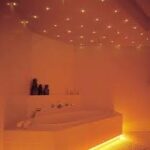 Een modern bad in een warm verlichte badkamer, versterkt door de betoverende LED Sterrenhemel (400 sterren) met 4,5 meter lange glasvezeldraden aan het plafond, creëert een ontspannen en gezellige sfeer.