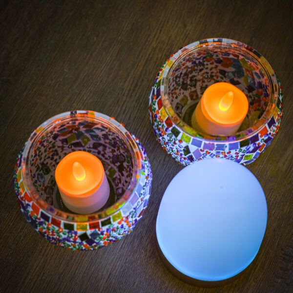 Twee mozaïek glazen kandelaars met oranje LED kaarsen staan op een houten oppervlak naast een Oplaadbaar LED waxine/theelichtje 175 uur waterproof warm wit, onderdeel van een 6-delige set met afstandsbediening.