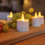Twaalf oplaadbare LED-was/theelichtjes (warm wit, waterdicht, 175 uur brandtijd) verlichten een houten plank met groene druiven en snacks en zorgen zo voor een warme, gezellige sfeer. Inclusief afstandsbediening.