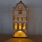 De Waxinelichthouder houten huis DORSETTO is een klein houten model met boogramen en een gebogen dak, van binnenuit verlicht door een LED waxinelichtje en ontworpen om op een plat oppervlak tegen een gewone muur te staan.