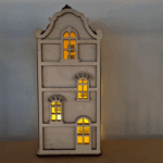 De Waxinelichthouder houten huis DORSETTO is een kleine, decoratieve kandelaar met boogramen en warmgele lichtjes die erachter schijnen, perfect om tegen een lichtgekleurde muur te plaatsen.