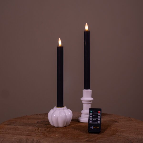 Twee beige oplaadbare LED dinerkaarsen (set van 2, brandduur 400 uur) zitten in witte houders - een pompoenvormig, een cilindervormig - op een houten oppervlak met een afstandsbediening ervoor, tegen een effen achtergrond.