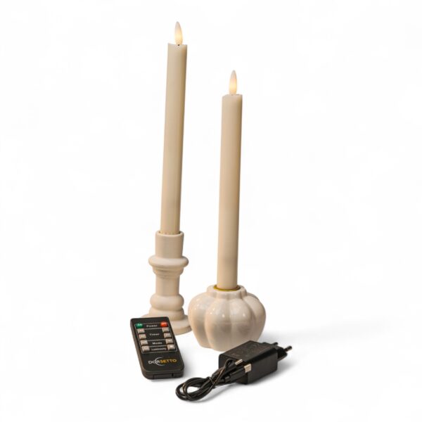 Twee crèmekleurige LED conische kaarsen in witte houders worden afgebeeld met een zwarte afstandsbediening en een voedingsadapter, alles op een witte achtergrond. De kaarsen hebben een realistisch vlameffect.