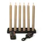 Sechs batteriebetriebene flammenlose Kerzen in einem schwarzen Ständer, alle angezündet, mit einer Fernbedienung und einem Stromadapter vor dem Ständer.