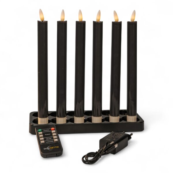 Sechs schwarze elektrische Kerzen mit flammenförmigen Glühbirnen sind in einem rechteckigen schwarzen Halter angeordnet. Davor befinden sich eine schwarze Fernbedienung und ein Steckernetzteil, alles auf weißem Hintergrund.