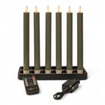 Ein Satz von sechs hohen, dunkelgrünen elektrischen Kerzen in einem schwarzen, rechteckigen Sockel, mit einer Fernbedienung und einem Stromadapter vor ihnen, alles auf weißem Hintergrund.