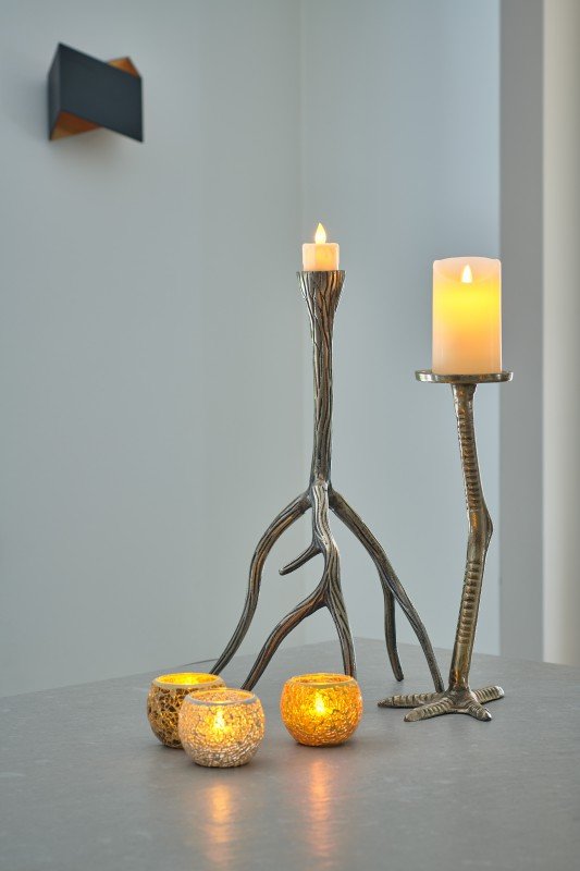 Zwei LED-Wachskerzen D12,5 × H15 CM (warmweiß, wiederaufladbar, mit Fernbedienung) stehen auf einer Fläche neben drei kleinen beleuchteten Glasvotiven in einem minimalistischen modernen Interieur.